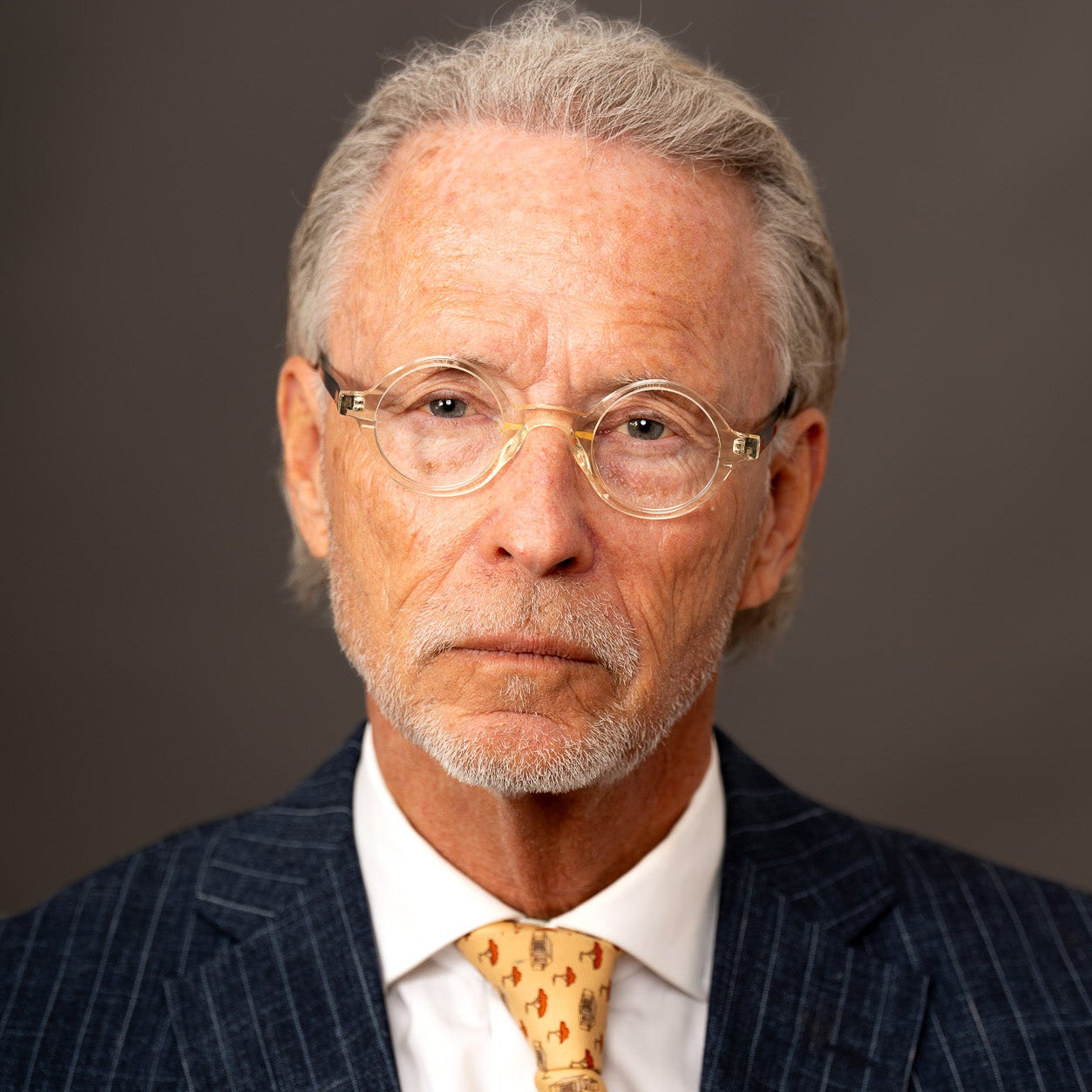 Man wearing a suit with a yellow tie against a dark background